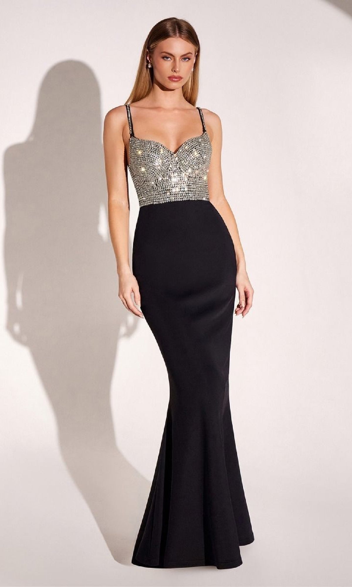 A woman stands against a plain background wearing the Beaded-Bodice Long Prom Dress: Amoris T9002, a fitted black mermaid gown featuring thin straps and a beaded bodice.